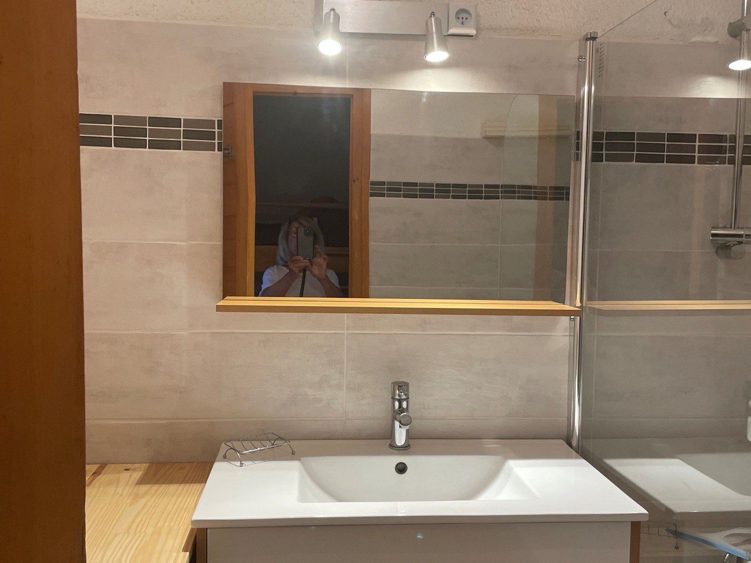 A bathroom with a large mirror, a sink, and a shower.