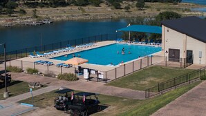 Una piscina con sillones de descanso y un edificio contiguo.