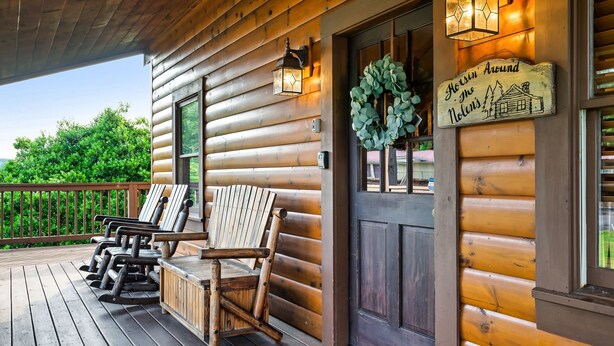 A wooden cabin with a porch featuring four Adirondack chairs, a lantern, and a welcome sign. - LOCATION*PET FRIENDLY*NEAR ATTRACTIONS*HOT TUB (Pigeon Forge)