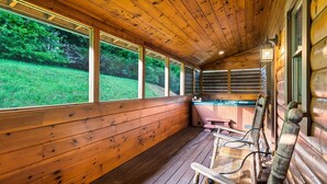 A wooden cabin interior with large windows, a hot tub, and wooden benches. - LOCATION*PET FRIENDLY*NEAR ATTRACTIONS*HOT TUB (Pigeon Forge)