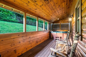 L’intérieur d’un chalet en bois, doté de grandes fenêtres, d’un bain à remous et de bancs en bois.