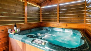 A wooden cabin with a hot tub, wooden walls, and a window with blinds. - LOCATION*PET FRIENDLY*NEAR ATTRACTIONS*HOT TUB (Pigeon Forge)