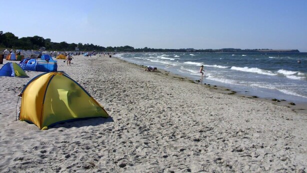 En strand med tält och människor.