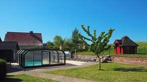 Ett poolområde med en glasvägg, en tegelvägg och en röd byggnad i bakgrunden.