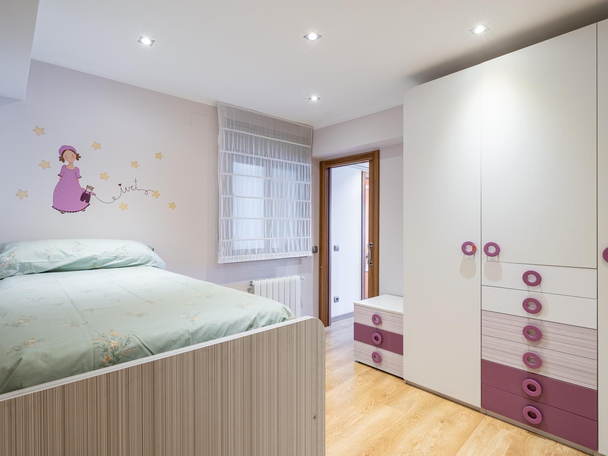 Een slaapkamer met een bed, een kledingkast en een decoratie aan de muur.