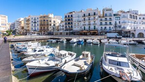 Marina con varias embarcaciones amarradas, rodeada de edificios de varios pisos con balcones.