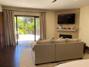 Un salon moderne avec un canapé beige, un téléviseur à écran plat fixé sur un mur en pierre et une cheminée.