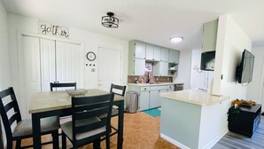 Een moderne keuken met een eethoek, met een klok, een bord met daarop 'Coffee Bar' en een aan de muur bevestigde televisie.