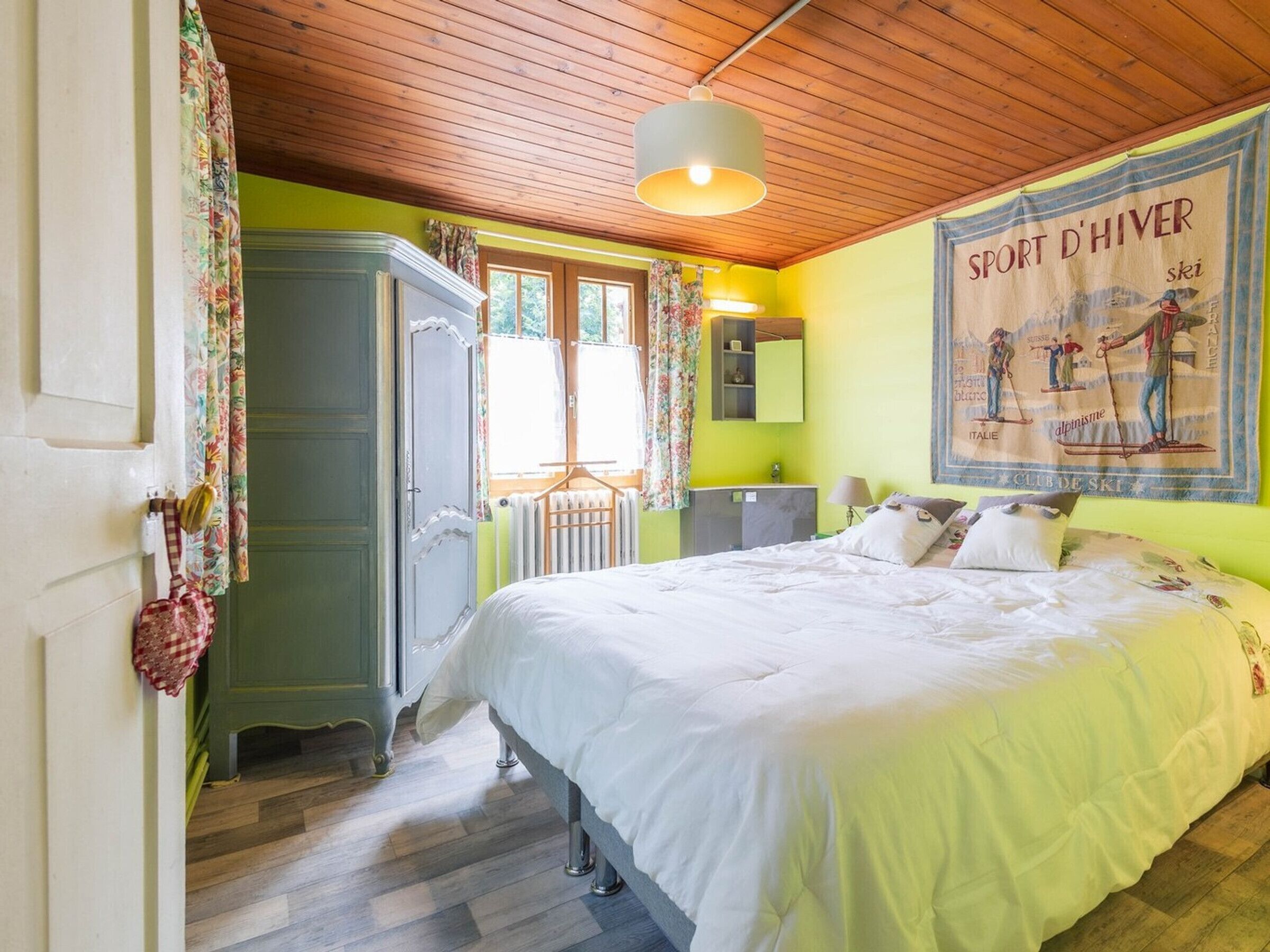 A bedroom with a bed, a wardrobe, a radiator, a mirror, and a poster on the wall.