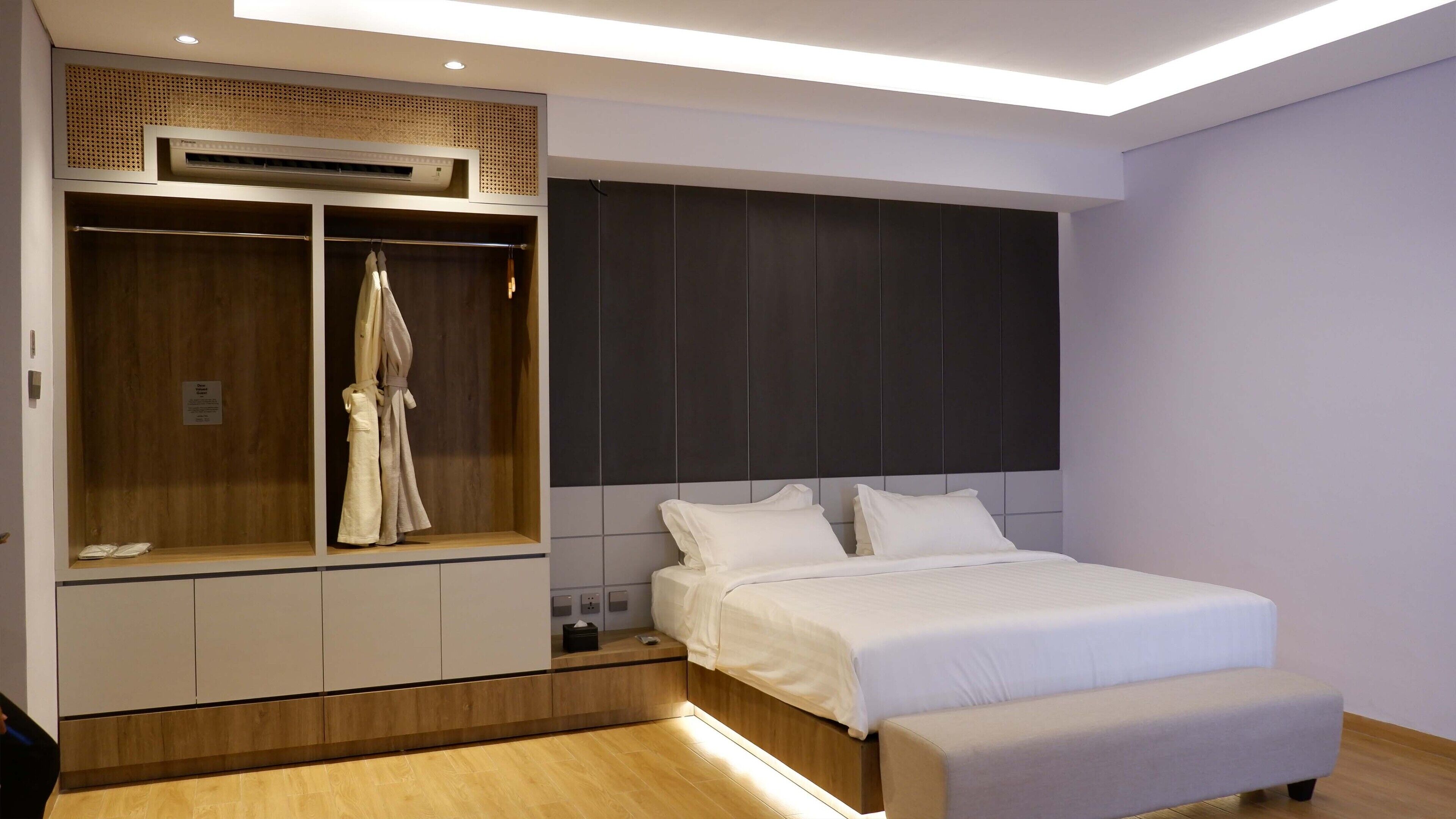 Un dormitorio moderno con una cama grande, un armario empotrado y aire acondicionado instalado en el techo.
