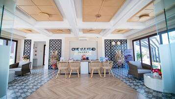 A reception area with a wooden reception desk, wicker chairs, and a patterned floor.