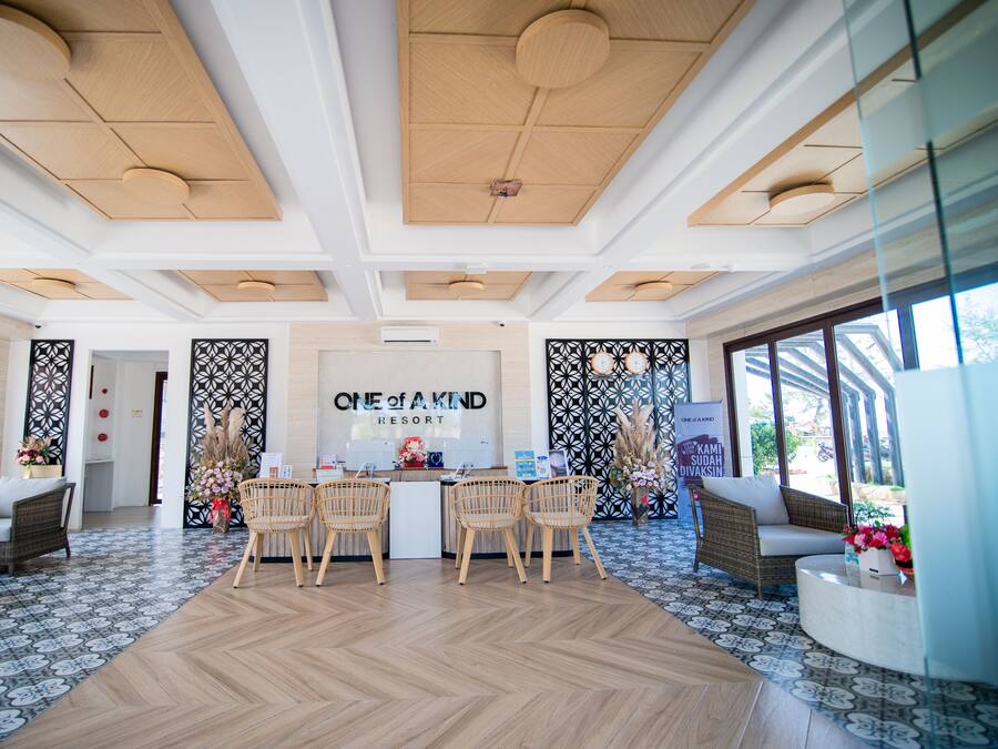 A reception area with a wooden reception desk, wicker chairs, and a patterned floor.