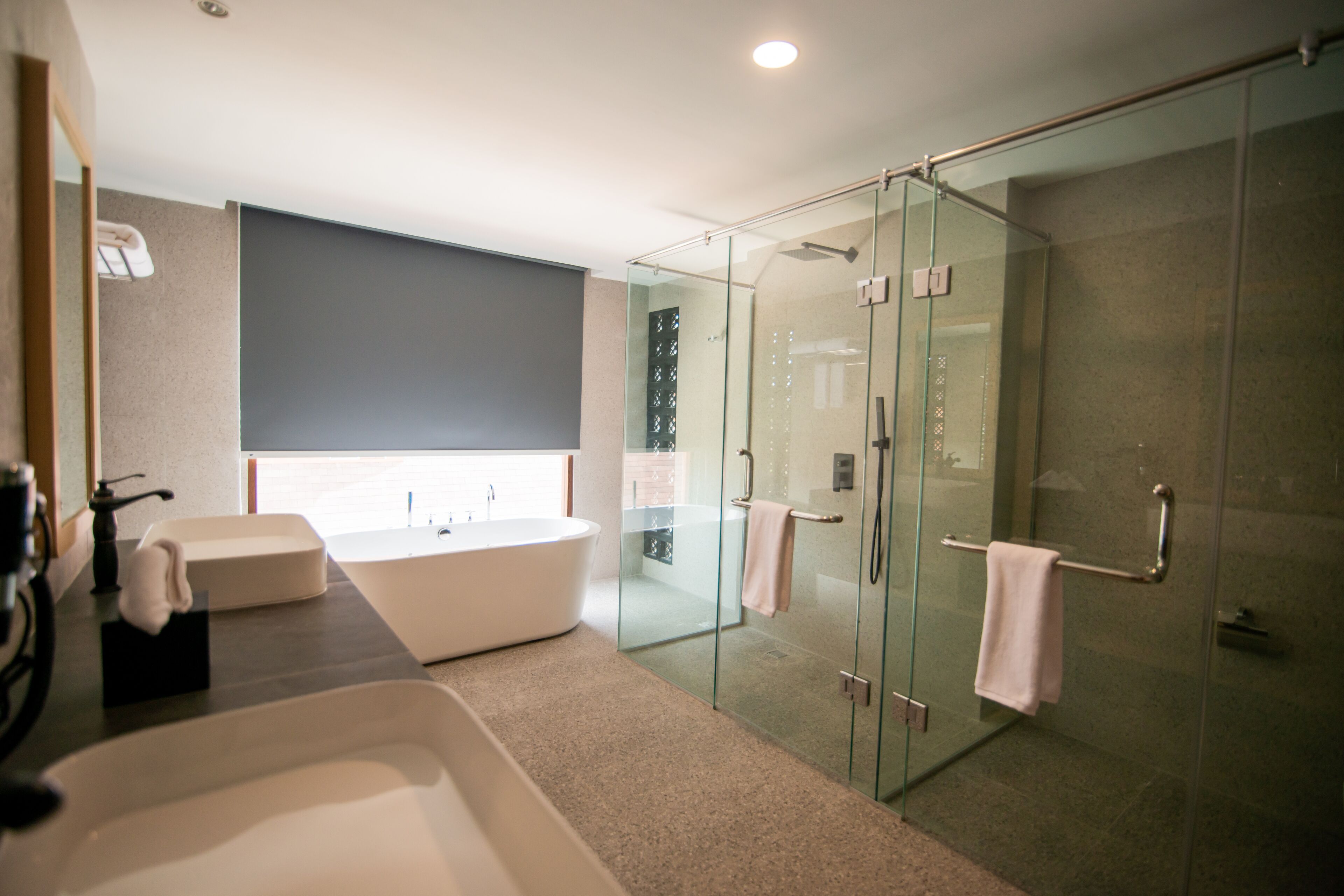 A modern bathroom with a glass-enclosed shower, a freestanding bathtub, and a vanity with a large mirror.