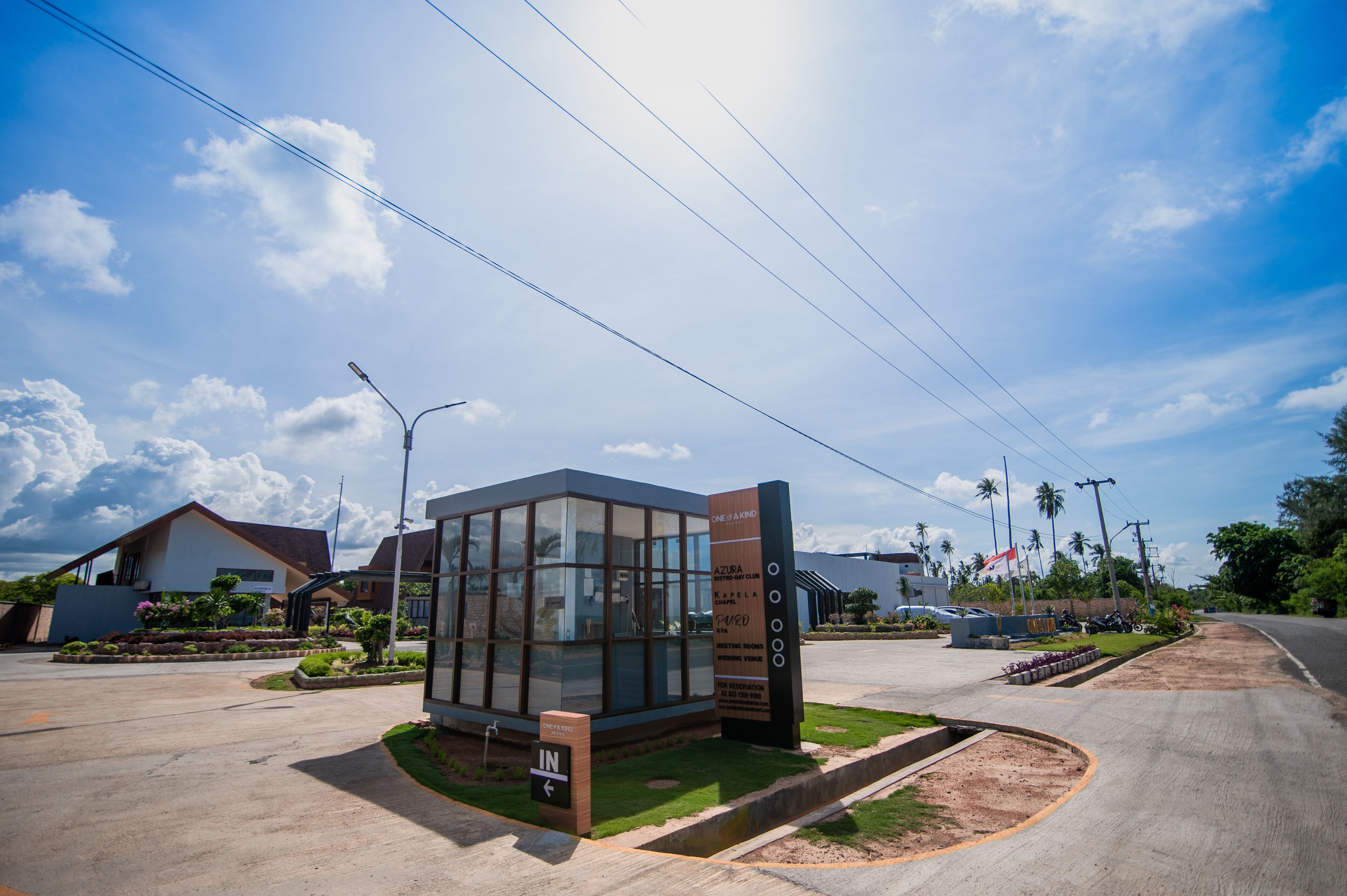 A modern building with a glass facade, surrounded by a landscaped area with a sign indicating amenities.