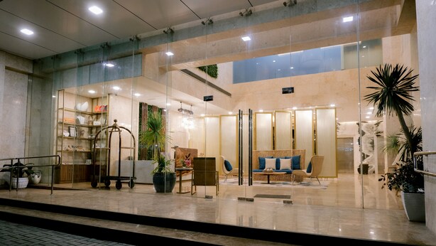 A modern hotel lobby with a glass entrance, a reception desk, seating area, and potted plants. - Goldberry Suites and Hotel Cebu (Cebu City)