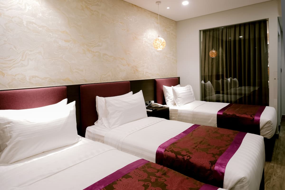 A hotel room with two beds, a marble wall, and a large window with curtains.