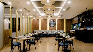 A restaurant interior with multiple tables and chairs, a central seating area with a bench, and a decorative wall with a rabbit logo. - Goldberry Suites and Hotel Cebu (Cebu City)