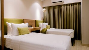A hotel room with two beds, a wooden headboard, a nightstand, and a window with curtains. - Goldberry Suites and Hotel Cebu (Cebu City)