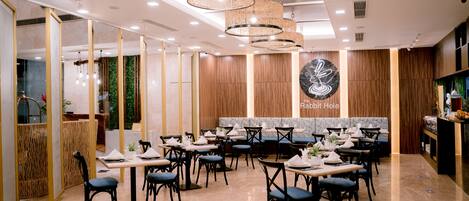 A restaurant with a modern interior, featuring wooden paneling, a central seating area, and a decorative wall with a logo.