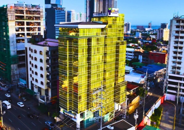 A multi-story building with a yellow facade, surrounded by other buildings and a busy street. - Goldberry Suites and Hotel Cebu (Cebu City)