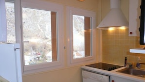 Eine kleine Küche mit Geschirrspüler, Spüle und einem Fenster mit Vorhängen.