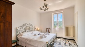 Una camera da letto con un letto, un termosifone, una finestra vista e un lampadario.