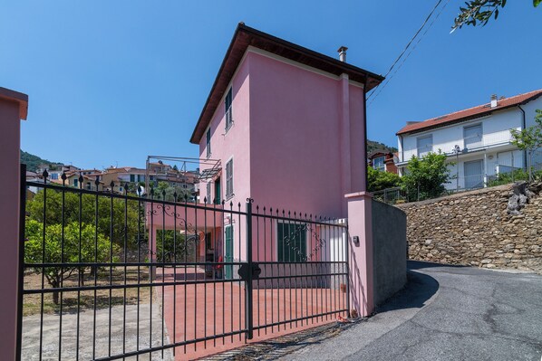 A pink building with a gated entrance, a stone wall, and a clear blue sky.