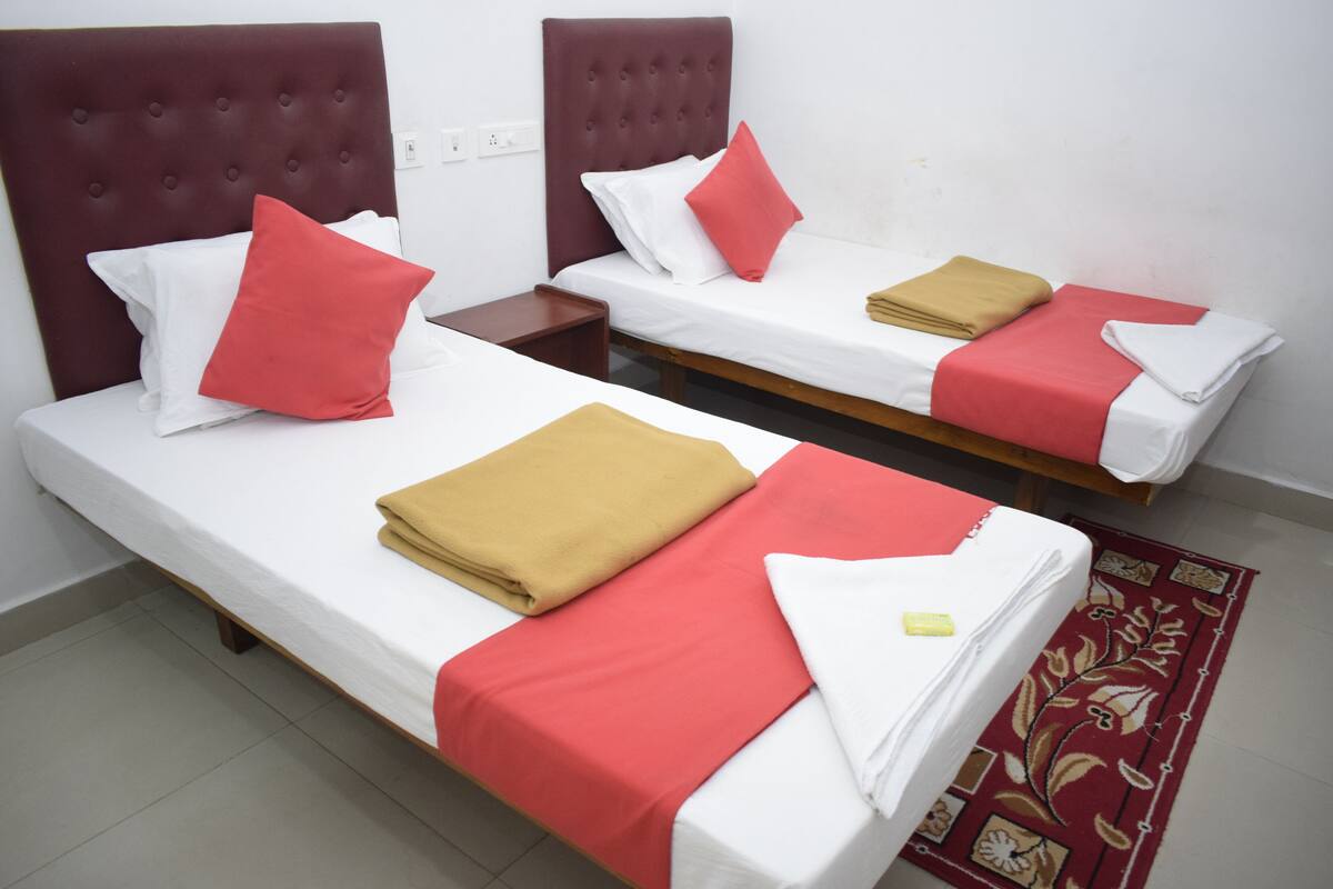 Two single beds with red and white bedding, a brown headboard, and a red patterned rug.