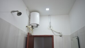 A bathroom with a white toilet, a shower, and a sink. - Hotel Jayaram (Chidambaram)