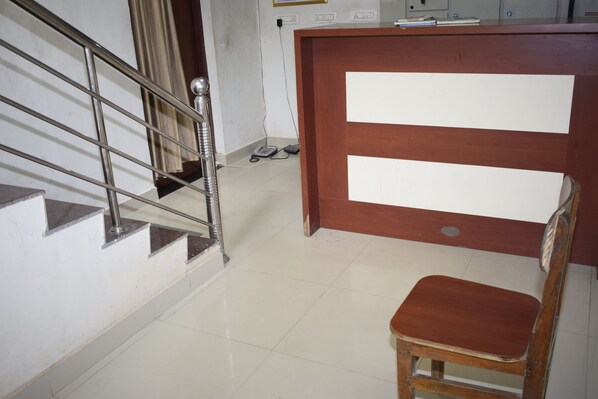 Uma área de recepção com uma mesa de madeira, um telefone e uma cadeira.
