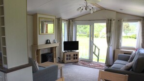 A cozy living room with a fireplace, television, and seating area. - Mountain View - luxury cabin with spectacular alpine and loch views (Taynuilt)