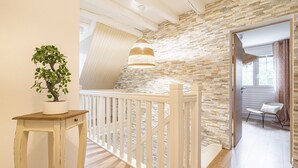 A staircase with a white railing leading to a room with a stone wall and a hanging light fixture. - Property with indoor pool 15min DISNEYLAND (Crécy-la-Chapelle)