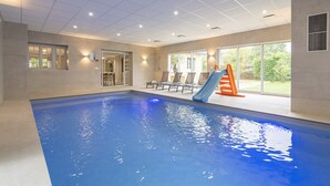 An indoor swimming pool with a slide, lounge chairs, and a view of the outdoors. - Property with indoor pool 15min DISNEYLAND (Crécy-la-Chapelle)