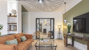 A modern living room with a sofa, coffee table, and a TV mounted on the wall. - Property with indoor pool 15min DISNEYLAND (Crécy-la-Chapelle)