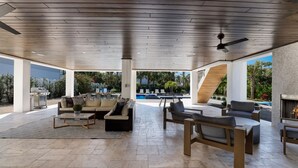 Et rummeligt udendørs opholdsområde med pool, moderne møbler og et træloft.