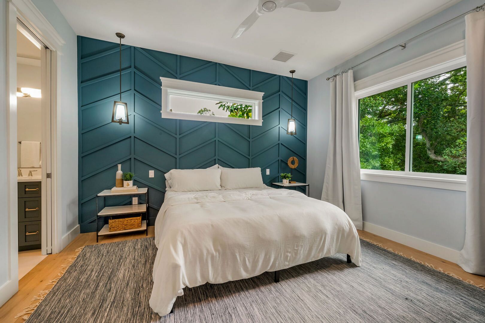 A bedroom with a bed, a nightstand, a dresser, a window, and a ceiling fan.