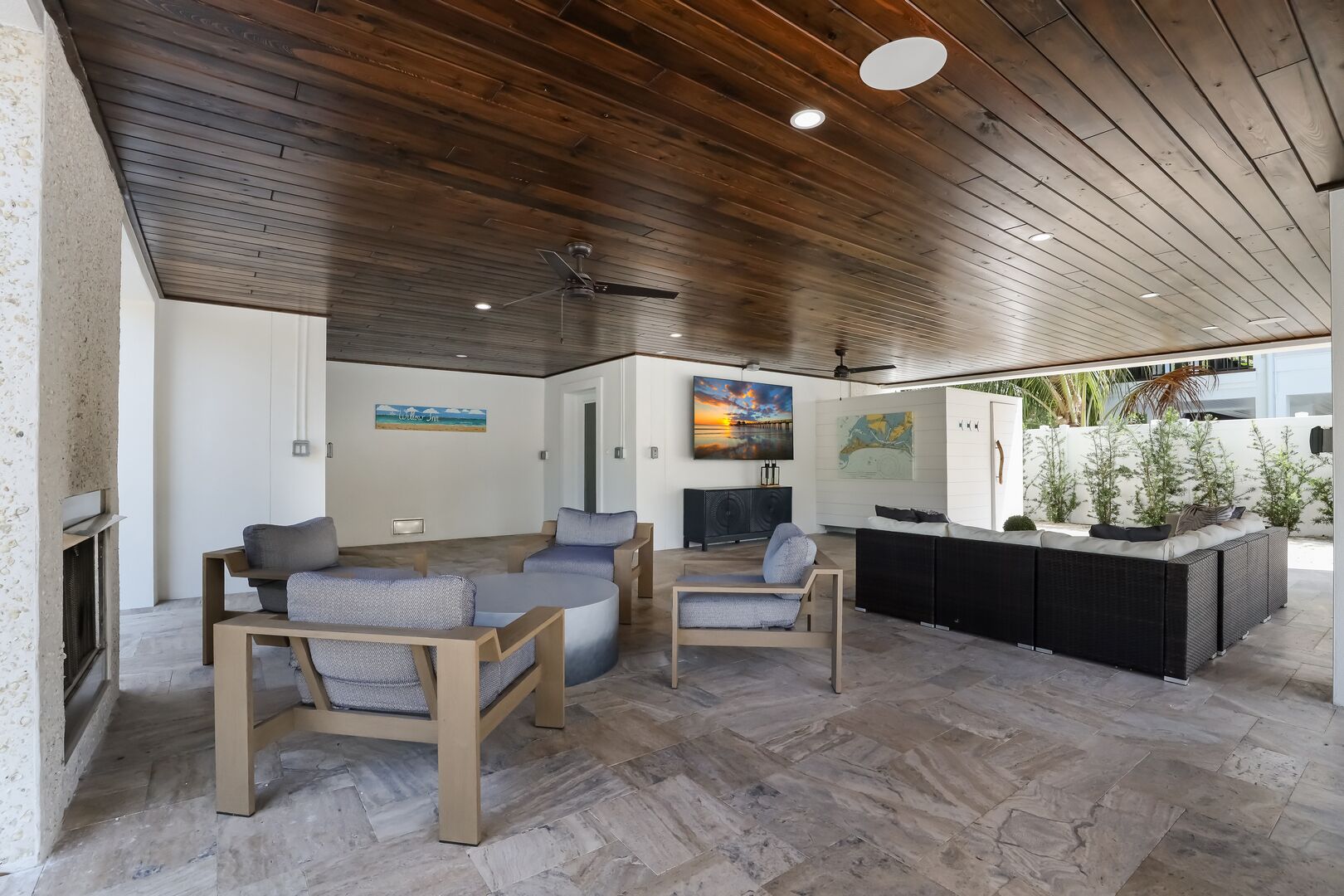 Una sala de estar moderna con techo de madera, un comedor y una cocina con una isla negra.
