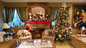 Un salon chaleureux avec une cheminée, un sapin de Noël et diverses décorations de fêtes.