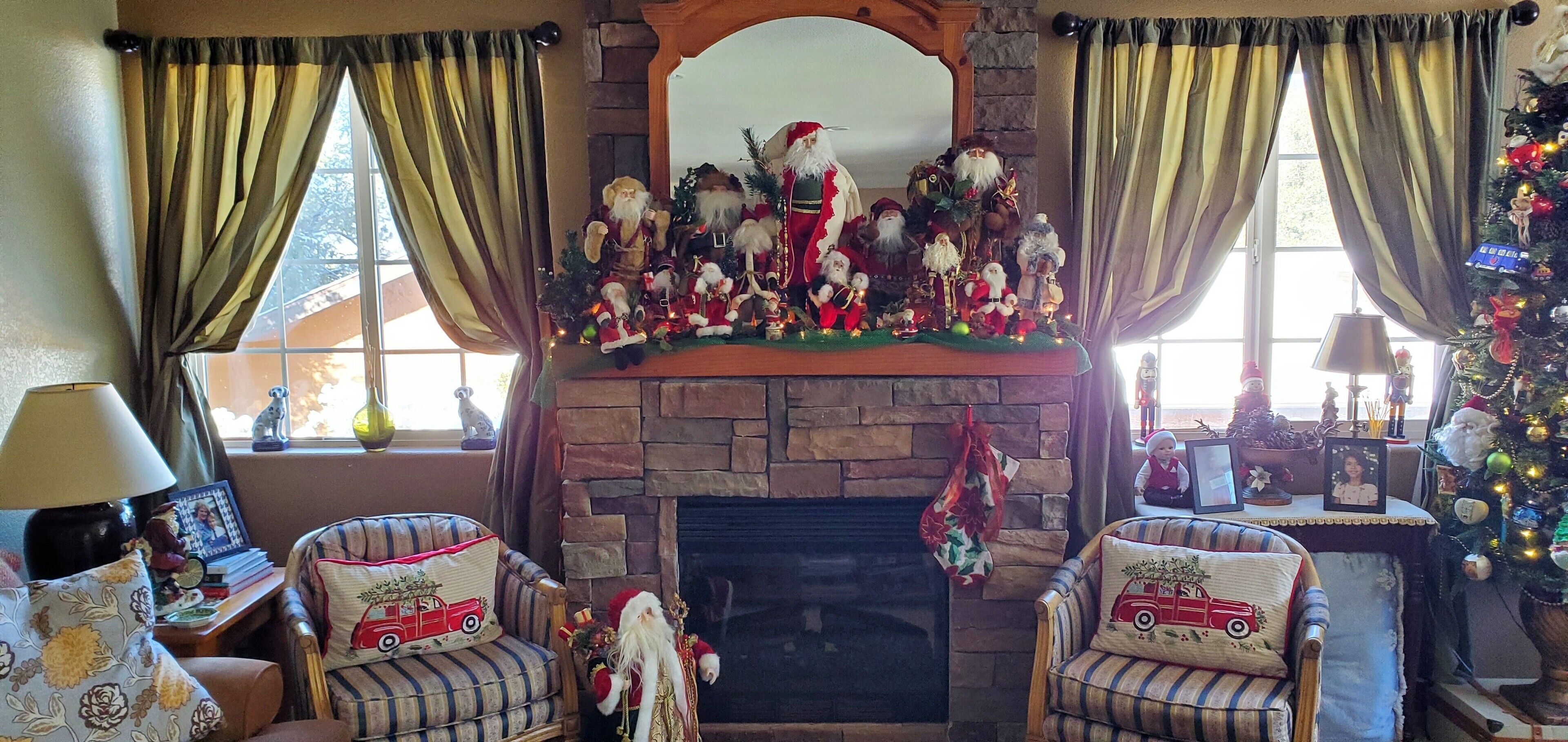 A cozy living room with a fireplace, two armchairs, and a Christmas tree.