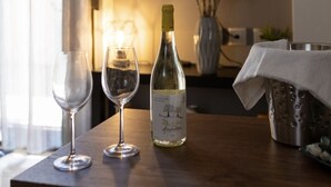 Uma mesa com duas taças de vinho, uma garrafa de vinho e uma vela acesa.