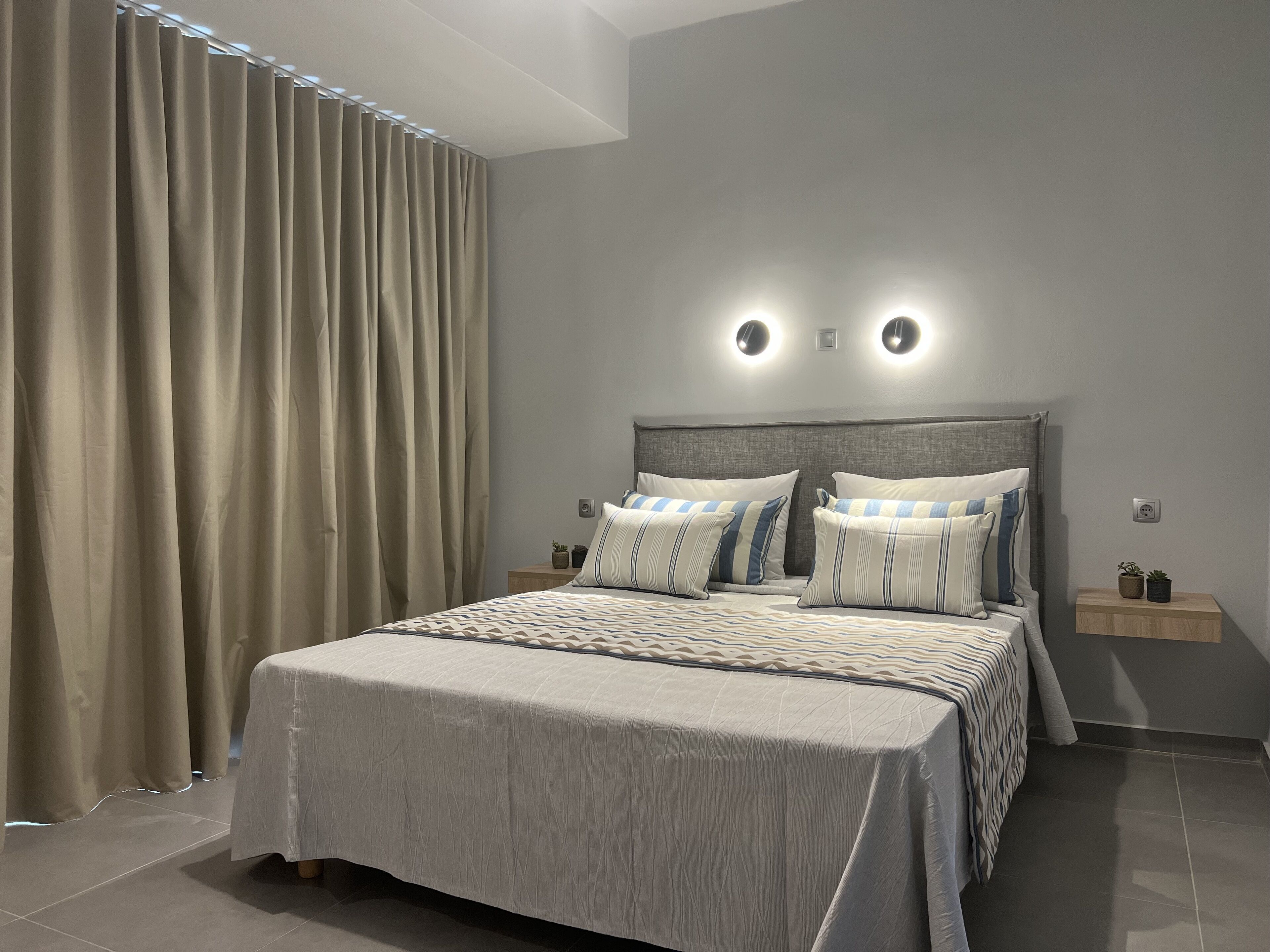 A modern bedroom with a large bed, two bedside tables, and a headboard with integrated lighting.