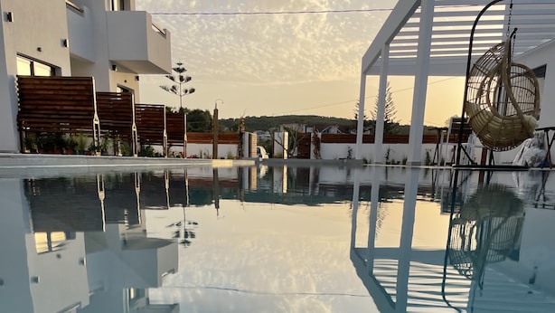 A modern pool area with clear water reflecting the sky and surrounding buildings. - Kimiro Hotel Tsilivi (Zakynthos)