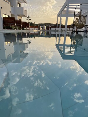 A modern pool area with clear water reflecting the sky and surrounding buildings.