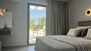 A modern bedroom with a bed, a nightstand, a mirror, and a view of the outdoors. - Kimiro Hotel Tsilivi (Zakynthos)