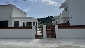A modern residential area with white buildings, a gated entrance, and a clear sky. - Kimiro Hotel Tsilivi (Zakynthos)