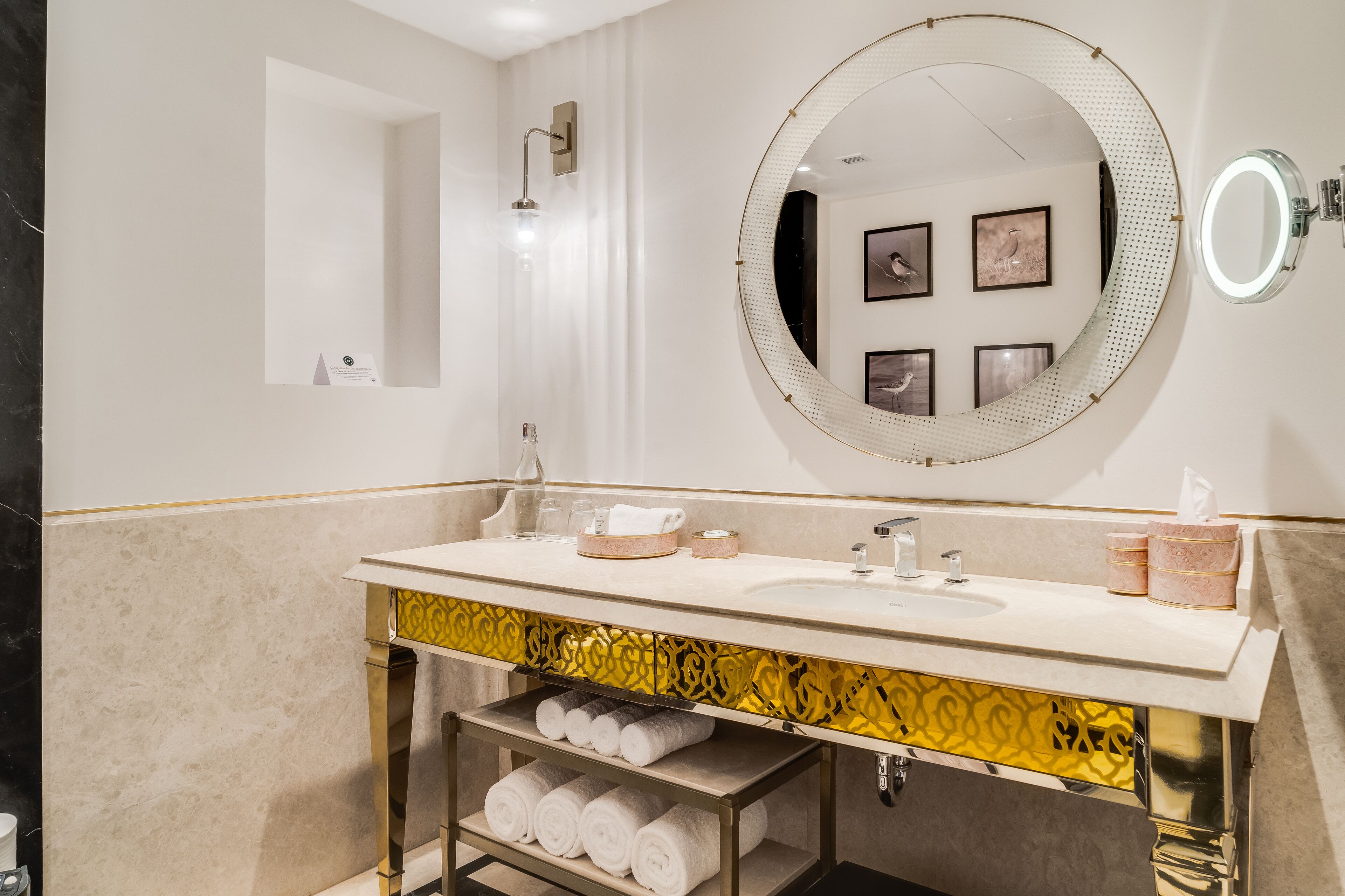 Un baño moderno con un espejo redondo grande, un lavamanos y un perchero para toallas.
