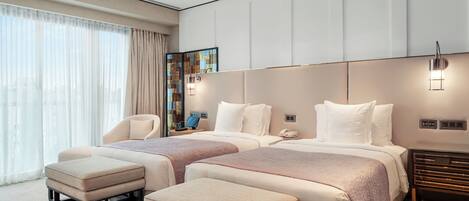 Una habitación de hotel moderna con dos camas, un ventanal con cortinas, una mesita de noche con lámpara y un espejo decorativo.