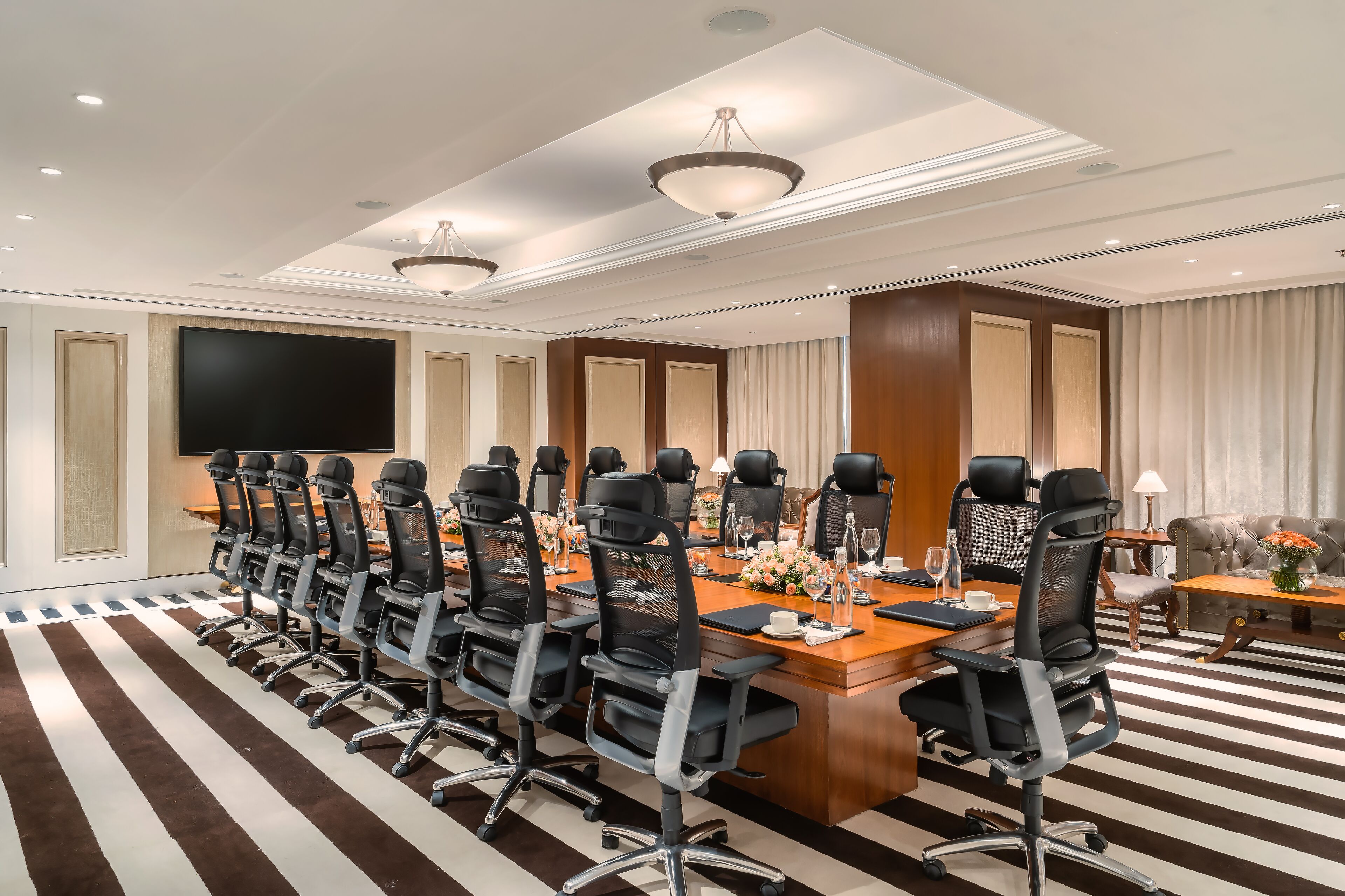 Une salle de conférence équipée d’une longue table, de nombreuses chaises, d’un grand écran et d’un canapé.