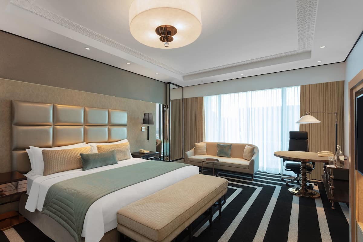 Ein modernes Hotelzimmer mit einem großen Bett, einer Couch, einem Schreibtisch und einem Fernseher.