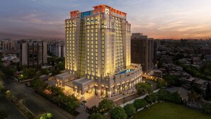 Een hoog hotel met meerdere verdiepingen, een zwembad op het dak en een goed verlichte gevel.